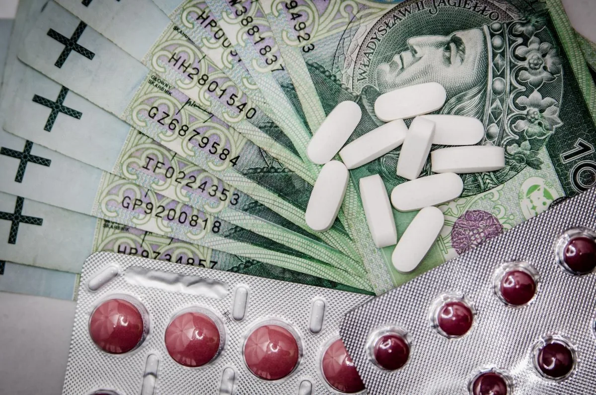 Loose white tablets and blister packs of pills lying on banknotes.