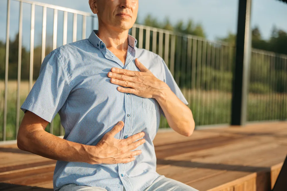 A man practices mindful breathing with one hand on his chest and one on his abdomen