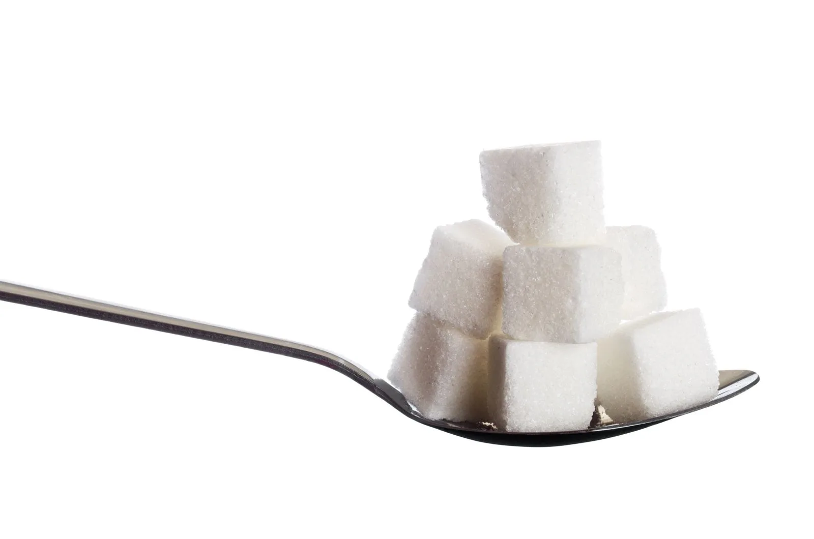 Stack of white sugar cubes piled on a metal spoon against a white background